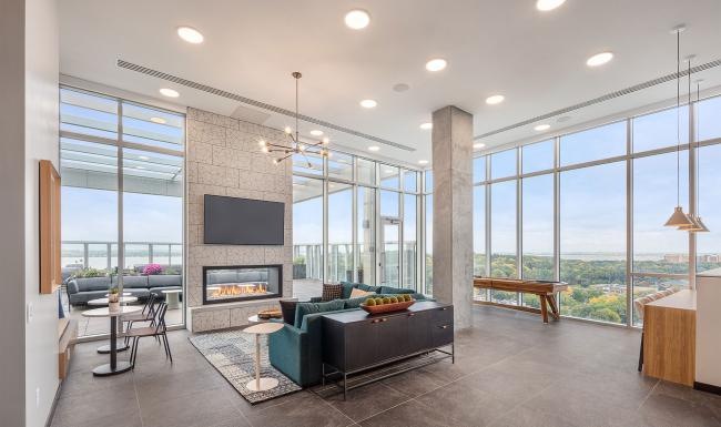 a lounge with a fireplace tv seating and large windows