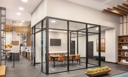 Glass-enclosed apartment conference room with marble table and leather chairs