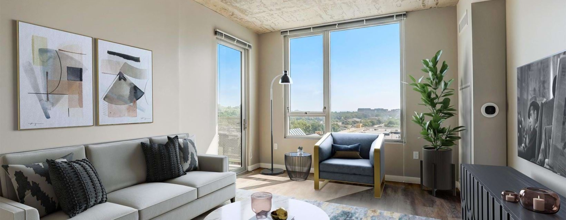 One-bedroom living room with gray sofa, blue chair, and balcony city views